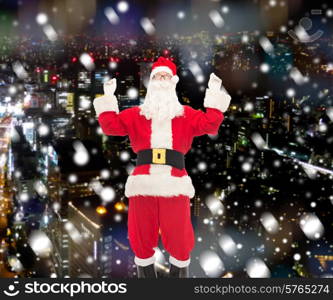 christmas, holidays and people concept - man in costume of santa claus having fun over snowy city background