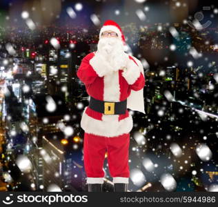 christmas, holidays and people concept - man in costume of santa claus with bag making hush gesture over snowy night city background