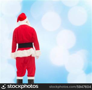 christmas, holidays and people concept - man in costume of santa claus from back over blue lights background