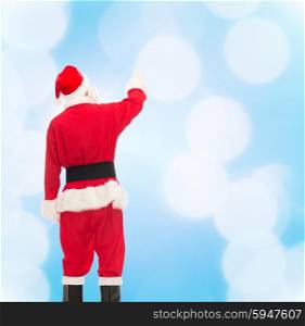 christmas, holidays and people concept - man in costume of santa claus pointing finger from back over blue lights background