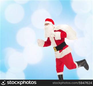 christmas, holidays and people concept - man in costume of santa claus running with bag over blue lights background