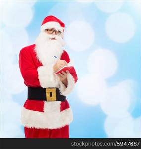 christmas, holidays and people concept - man in costume of santa claus with notepad and pen over blue lights background