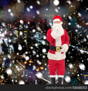 christmas, holidays and people concept - man in costume of santa claus making hush gesture over snowy night city background