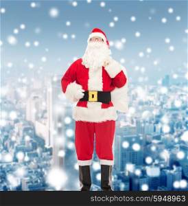 christmas, holidays and people concept - man in costume of santa claus with bag over snowy city background