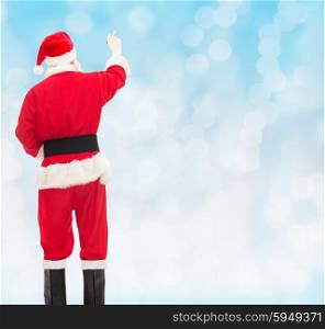 christmas, holidays and people concept - man in costume of santa claus writing something from back over blue lights background