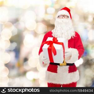 christmas, holidays and people concept - man in costume of santa claus with gift box over lights background