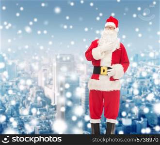 christmas, holidays and people concept - man in costume of santa claus over snowy city background