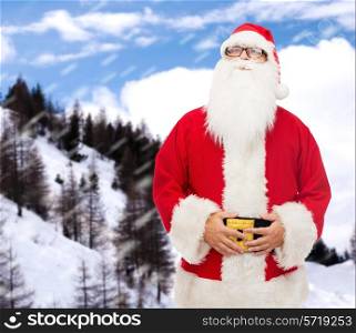 christmas, holidays and people concept - man in costume of santa claus over snowy mountains background