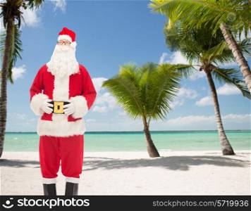 christmas, holidays and people concept - man in costume of santa claus over tropical beach background