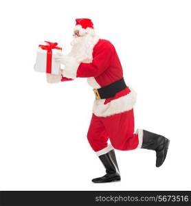 christmas, holidays and people concept - man in costume of santa claus running with gift box