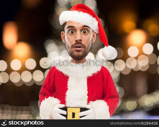 christmas, holidays and people concept - man in santa claus costume over lights background (funny cartoon style character with big head). man in santa claus costume over christmas lights