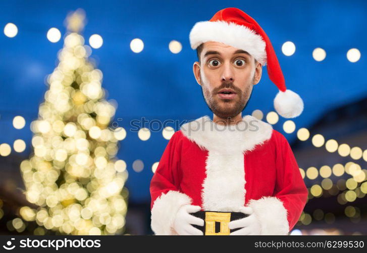 christmas, holidays and people concept - man in santa claus costume over lights background (funny cartoon style character with big head). man in santa claus costume over christmas lights