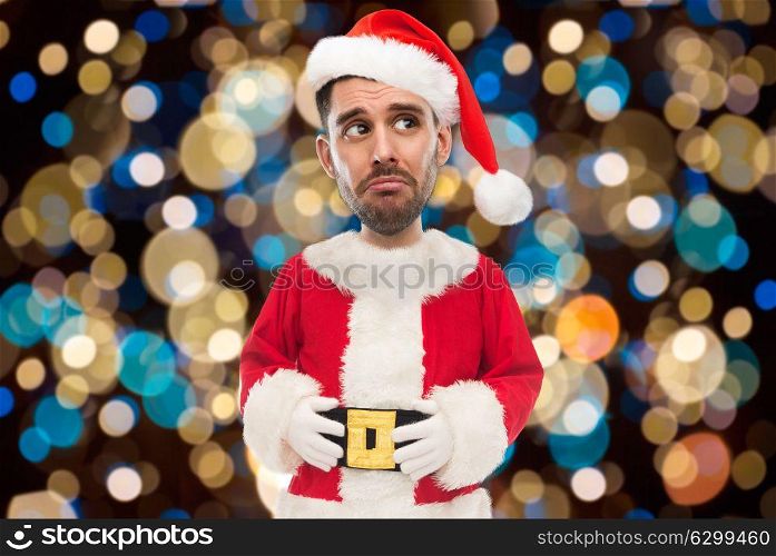 christmas, holidays and people concept - sad man in santa claus costume over lights background (funny cartoon style character with big head). sad man in santa costume over christmas lights