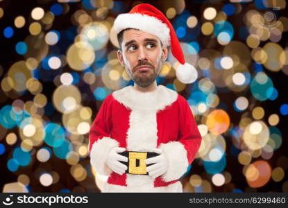 christmas, holidays and people concept - sad man in santa claus costume over lights background (funny cartoon style character with big head). sad man in santa costume over christmas lights