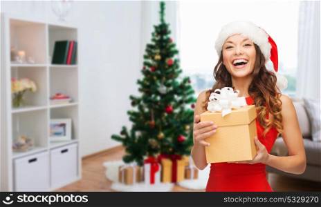 christmas, holidays and people concept- smiling woman in santa hat with gift. smiling woman in santa hat with christmas gift