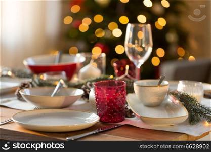 christmas, holidays and table setting concept - glass and tableware for festive dinner at home. table setting for christmas dinner at home