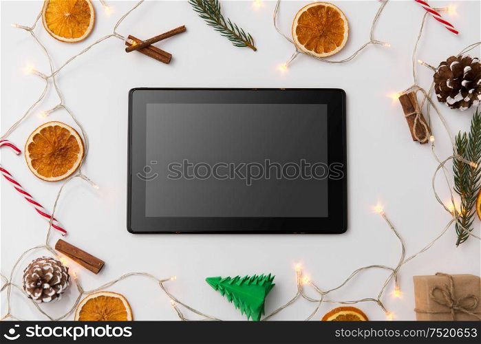 christmas, holidays and technology concept - tablet computer, garland and decorations on white background. tablet computer, garland and christmas decorations