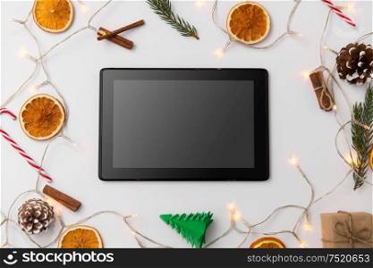 christmas, holidays and technology concept - tablet computer, garland and decorations on white background. tablet computer, garland and christmas decorations