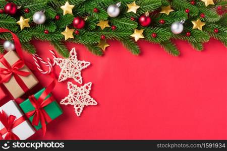 Christmas holidays background composition, Xmas greeting card with the view from above fir tree branch ornament decorations and gift boxes on red table background with copy space, New year concept