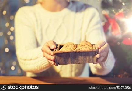 christmas, holidays, baking, people and food concept - close up of woman with oat cookies sitting at wooden table at home. close up of woman with oat cookies at home