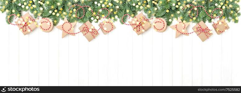 Christmas holidays banner with golden lights. Christmas tree branches and gift boxes on wooden background