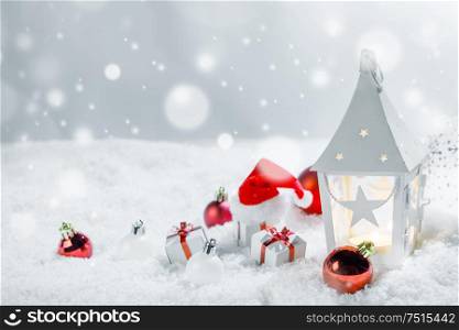 Christmas holidays card with gifts , balls , sants claus hat and glowing lantern in snow. Christmas decor in snow