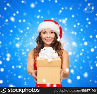 christmas, holidays, celebration and people concept - smiling woman in red dress with gift box over blue snowy background