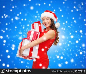 christmas, holidays, celebration and people concept - smiling woman in red dress with gift boxes over blue snowy background