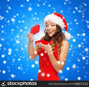 christmas, holidays, celebration and people concept - smiling woman in red dress with small gift box over blue snowy background