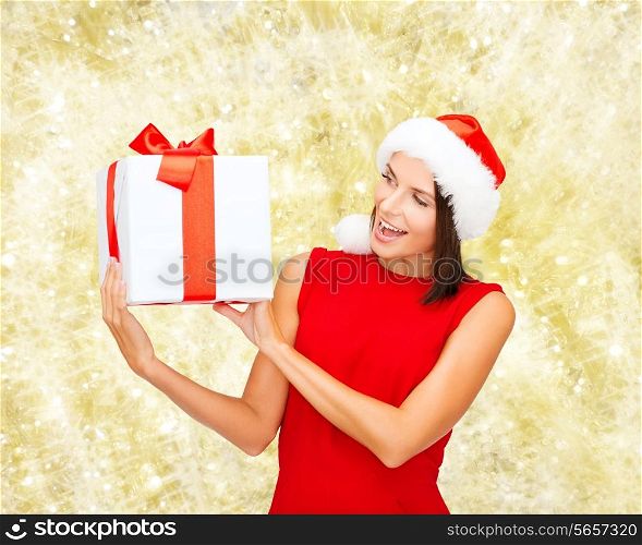 christmas, holidays, celebration and people concept - smiling woman in red dress with gift box over yellow lights background