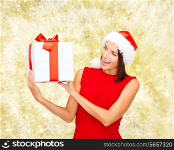 christmas, holidays, celebration and people concept - smiling woman in red dress with gift box over yellow lights background