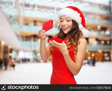 christmas, holidays, celebration and people concept - smiling woman in red dress with gift box over shopping center background