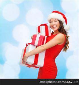 christmas, holidays, celebration and people concept - smiling woman in red dress with gift boxes over blue lights background