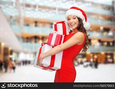 christmas, holidays, celebration and people concept - smiling woman in red dress with gift boxes over shopping center background