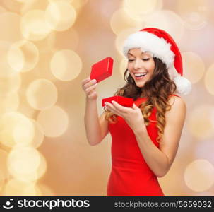 christmas, holidays, celebration and people concept - smiling woman in red dress with gift box over beige lights background