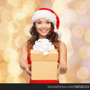 christmas, holidays, celebration and people concept - smiling woman in red dress with gift box over beige lights background