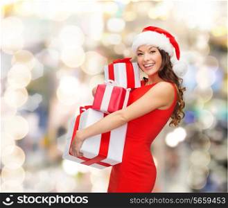 christmas, holidays, celebration and people concept - smiling woman in red dress with gift boxes over lights background