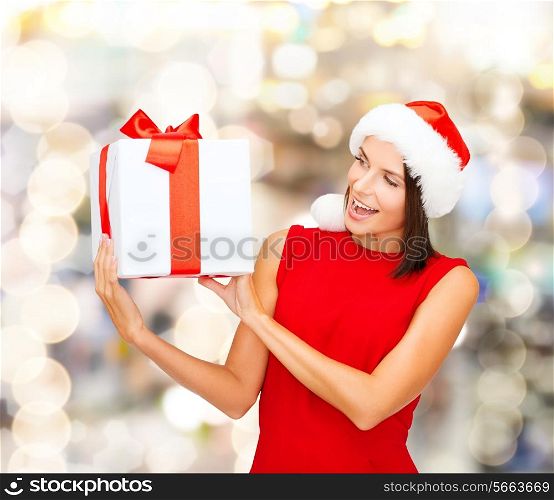 christmas, holidays, celebration and people concept - smiling woman in red dress with gift box over lights background