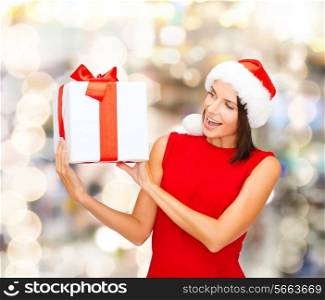 christmas, holidays, celebration and people concept - smiling woman in red dress with gift box over lights background