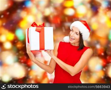 christmas, holidays, celebration and people concept - smiling woman in red dress with gift box over red lights background
