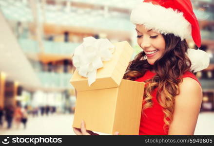 christmas, holidays, celebration and people concept - smiling woman in red dress with gift box over shopping center background