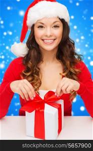 christmas, holidays, celebration and people concept - smiling woman in santa helper hat with gift box over blue snowy background