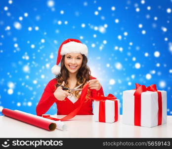 christmas, holidays, celebration, decoration and people concept - smiling woman in santa helper hat with scissors packing gift box over blue snowy background