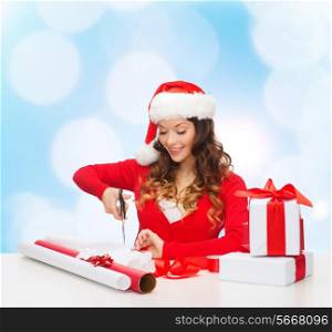 christmas, holidays, celebration, decoration and people concept - smiling woman in santa helper hat with scissors packing gift box over blue lights background