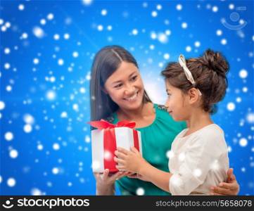 christmas, holidays, celebration, family and people concept - happy mother and child girl with gift box over blue snowy background