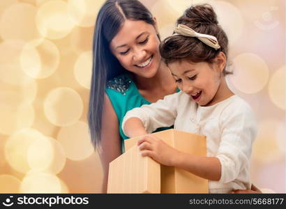 christmas, holidays, celebration, family and people concept - happy mother and child girl with gift box over beige lights background