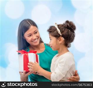 christmas, holidays, celebration, family and people concept - happy mother and child girl with gift box over blue lights background