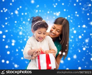 christmas, holidays, celebration, family and people concept - happy mother and girl with gift box over blue snowy background