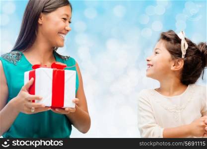 christmas, holidays, celebration, family and people concept - happy mother and girl with gift box over blue lights background