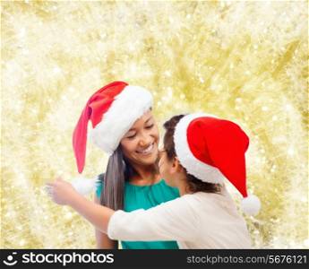 christmas, holidays, celebration, family and people concept - happy mother and little girl in santa helper hats over yellow lights background
